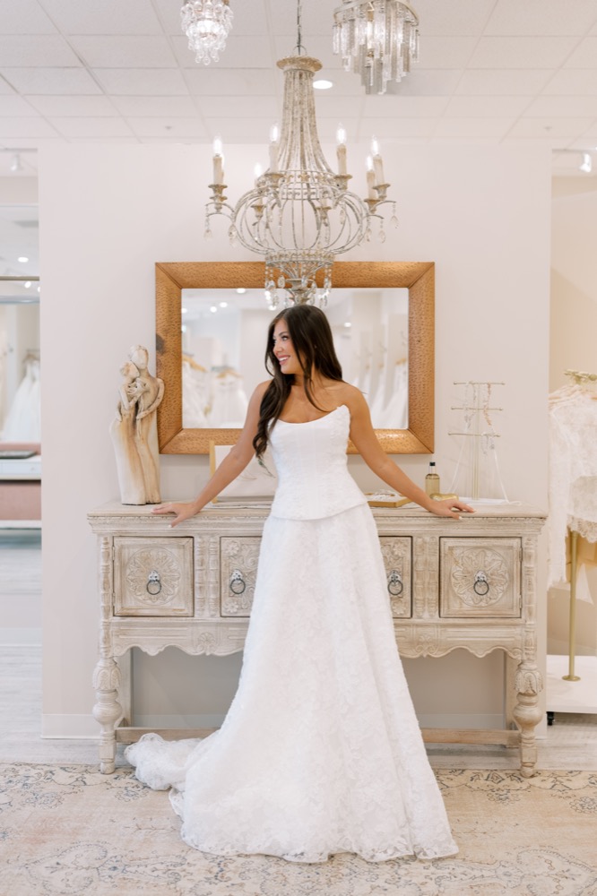 Bride standing in front of a chandelier and mirror in the showroom