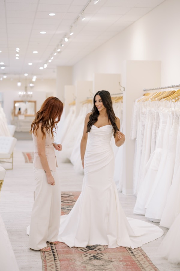 Bride in a fitted wedding gown speaking with her consultant at Brickhouse Bridal