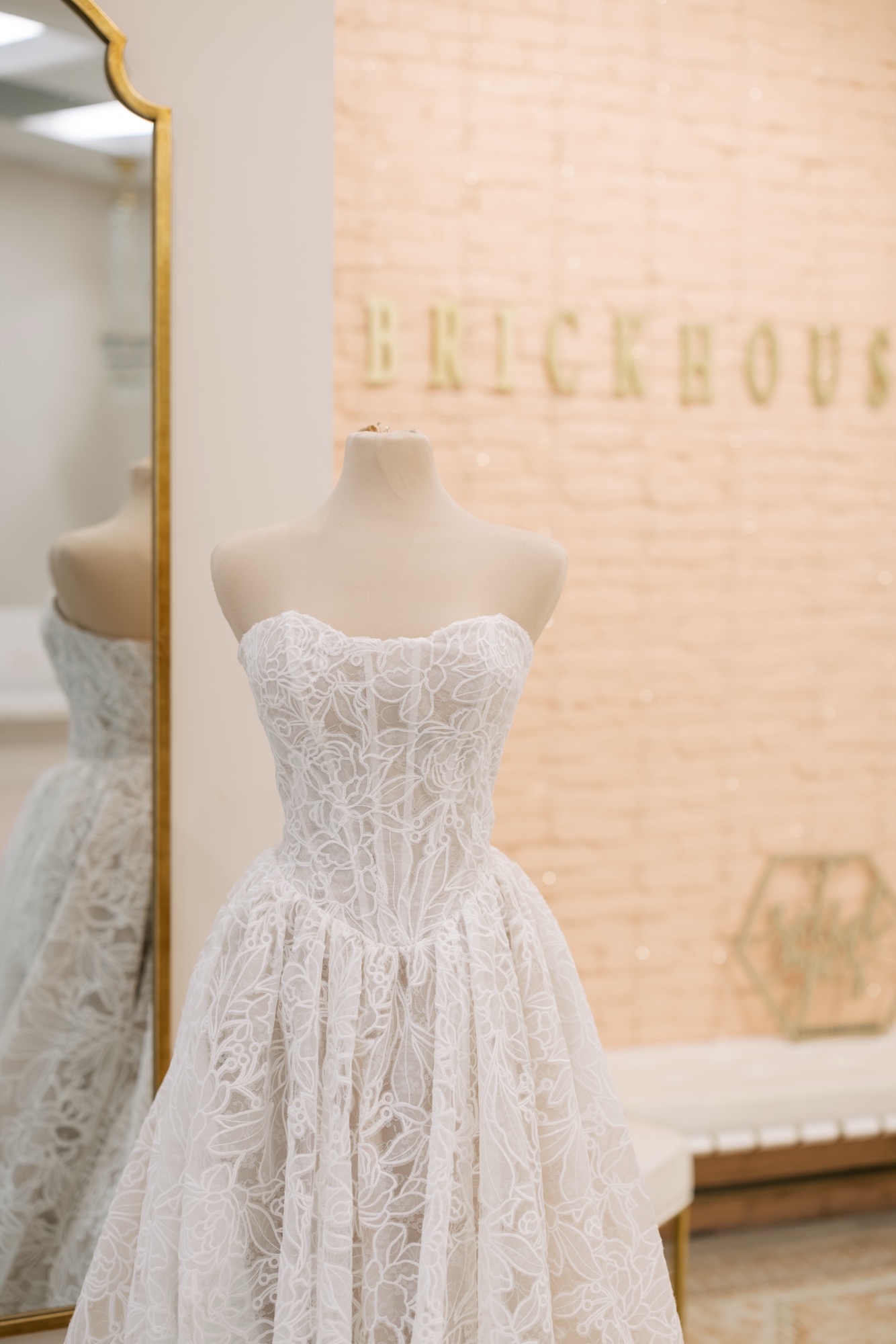 Wedding gown displayed on a mannequin in front of the Brickhouse Bridal wall