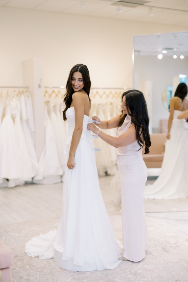 Consultant zipping up a bride's wedding gown