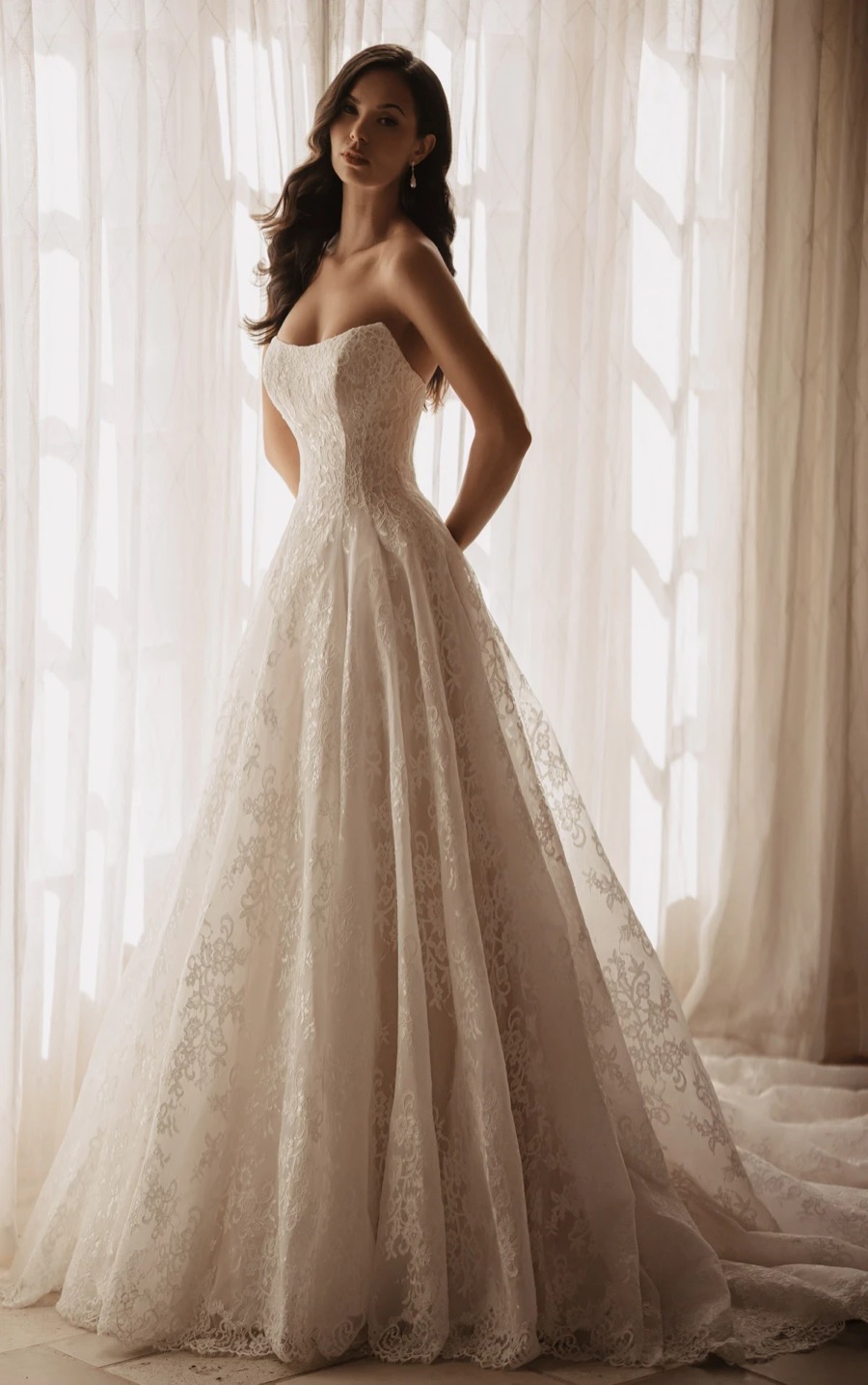 Bride in a Martina Liana strapless lace ballgown by a sheer curtained window