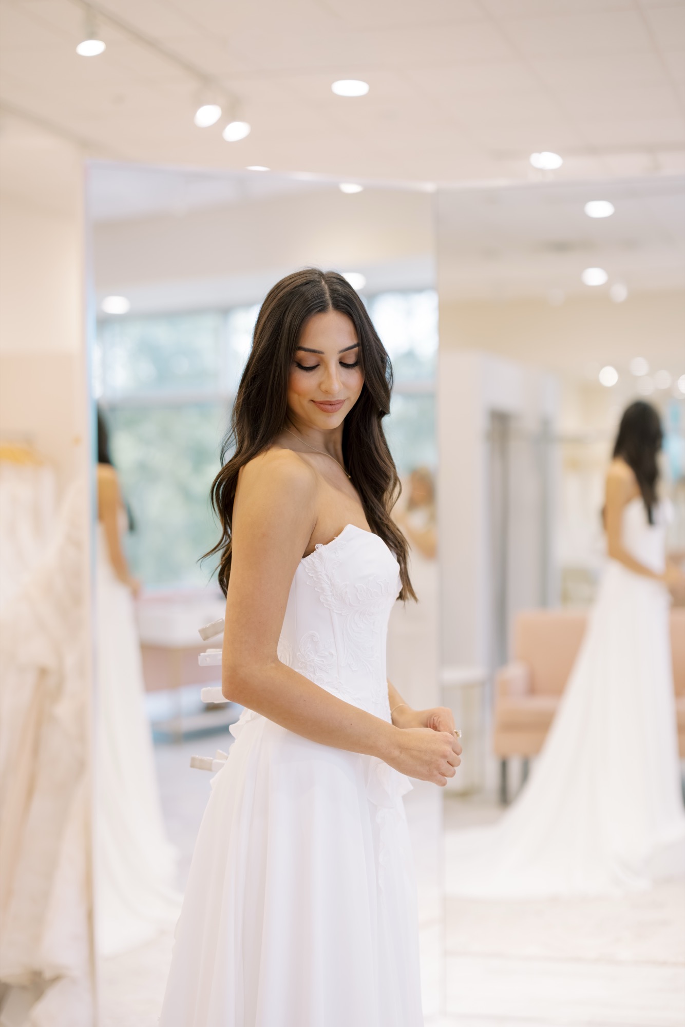 Bride in a wedding gown standing near a mirror